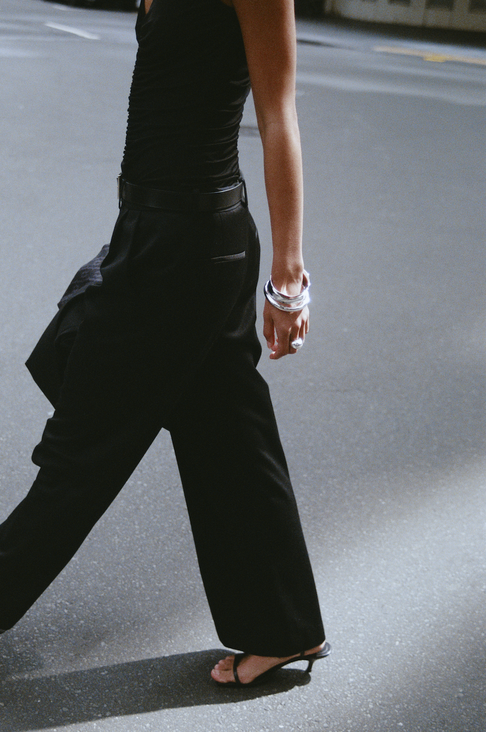 Model wearing the REBE Double Pleated Trouser in black — a full-length, wide-leg style with front pleats and a relaxed fit.