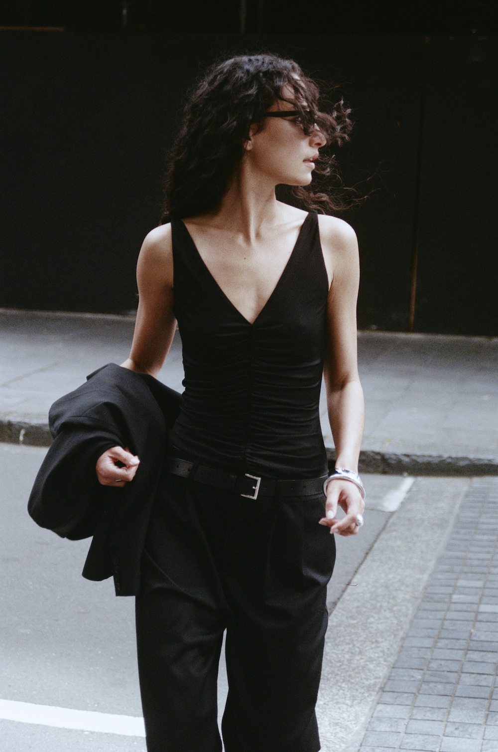 Model wearing the REBE Double Pleated Trouser in black — a full-length, wide-leg style with front pleats and a relaxed fit.