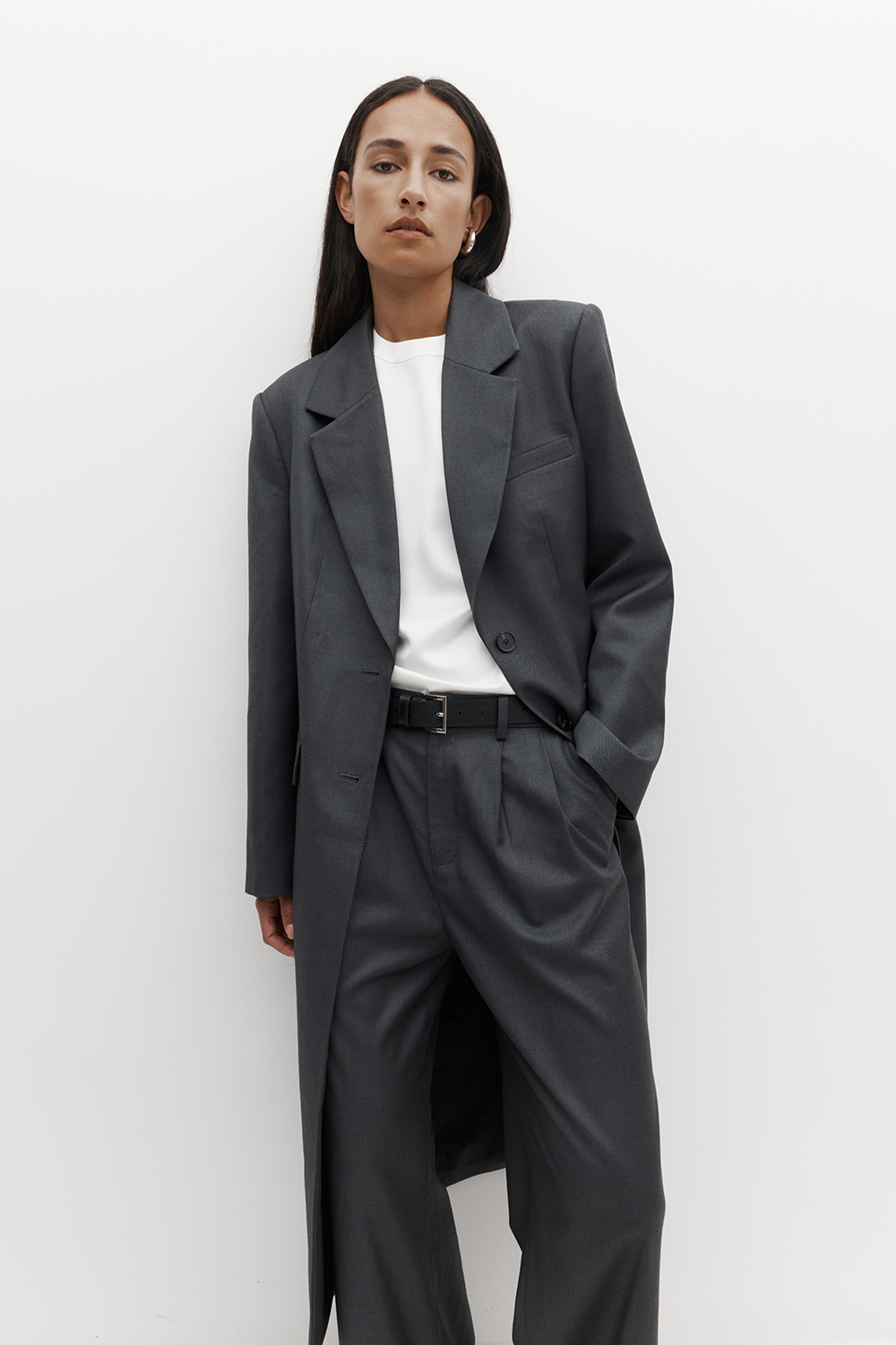 REBE’s Icon Coat in charcoal, styled on a model with tonal layers. Featuring sharp shoulders, a tailored silhouette, and full lining.