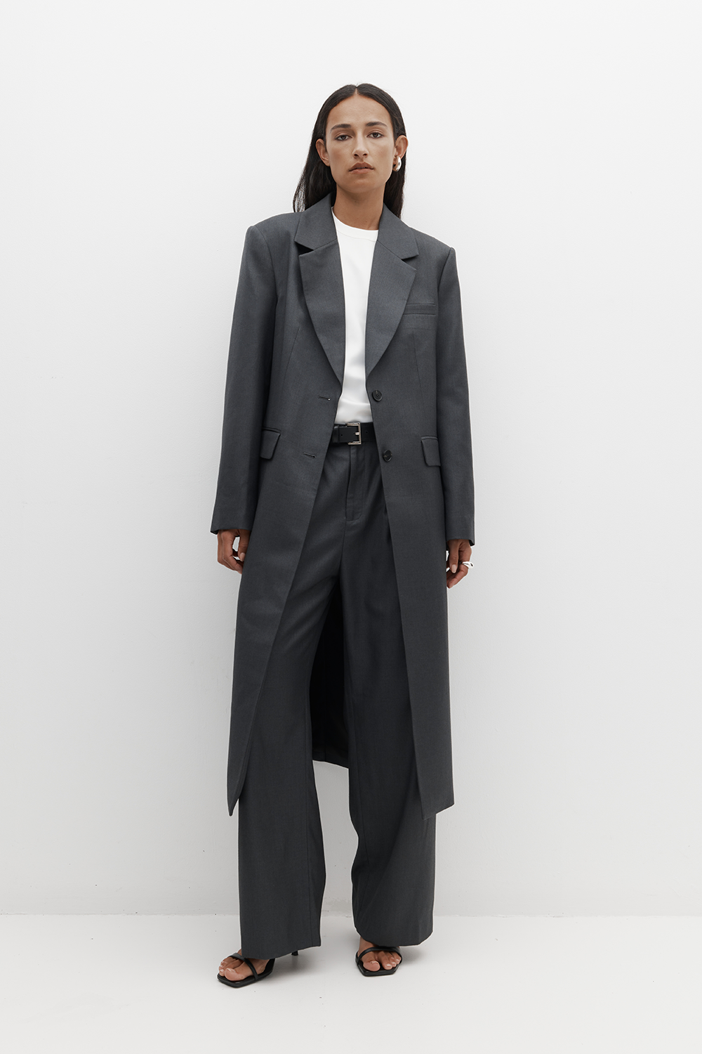 REBE’s Icon Coat in charcoal, styled on a model with tonal layers. Featuring sharp shoulders, a tailored silhouette, and full lining.